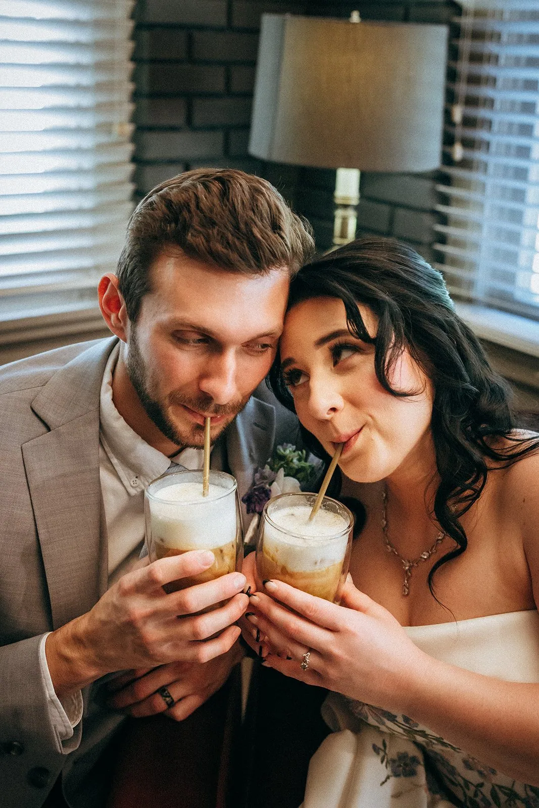 Bride and groom sharing iced lattes through gold straws