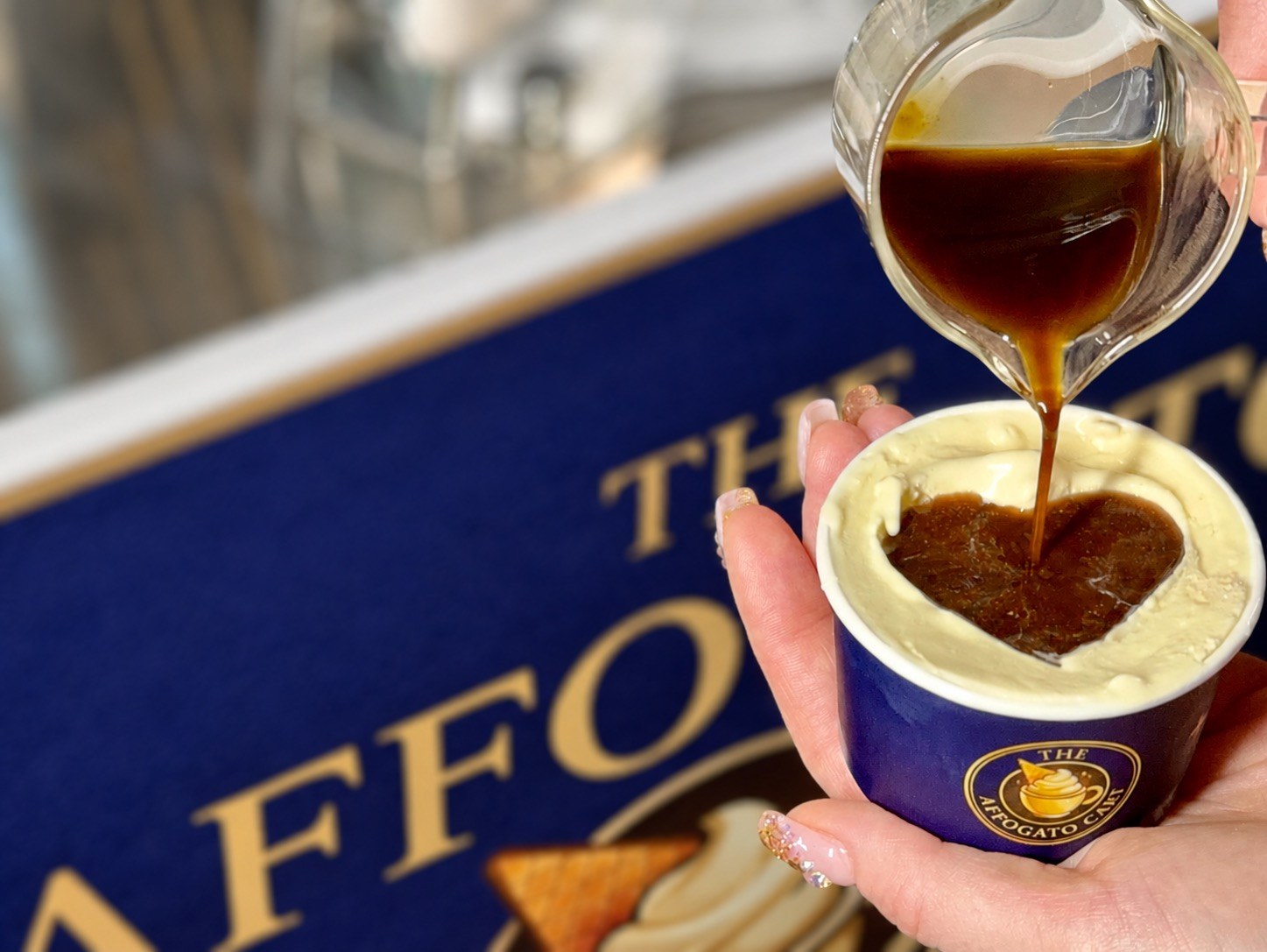 A Love Affogato being poured, with a heart drawn in the vanilla gelato, in front of The Affogato Cart